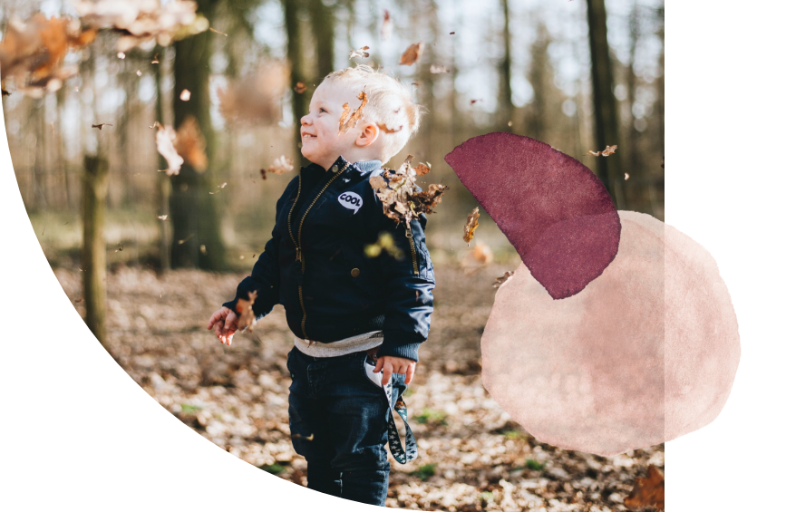 A child in a forest with dried leaves falling around them